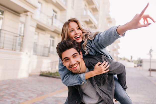 Pareja sonriente mirando hacia un futuro común, basado en disfrutar de la realidad y tener expectativas realistas.