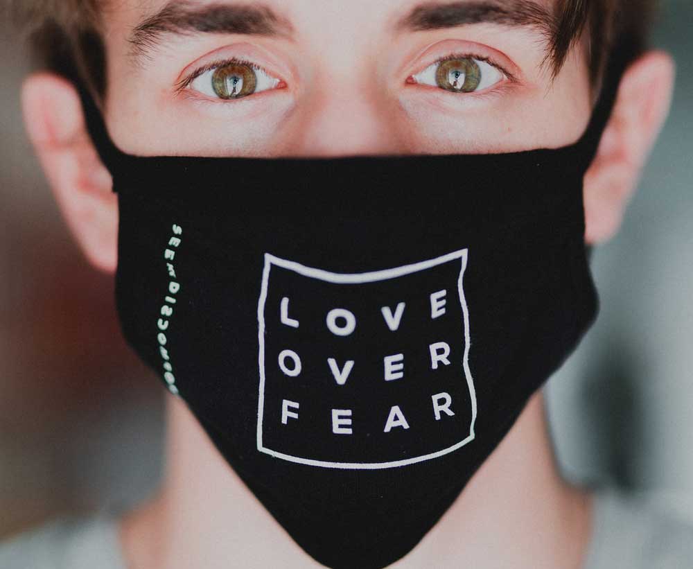 Hombre con mascarilla: Love over Fear. Amor frente a miedo. 