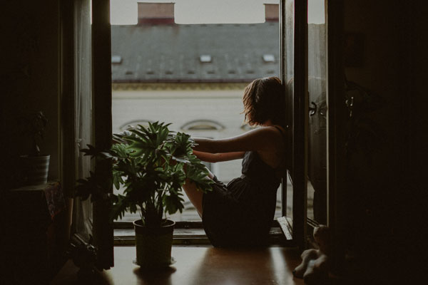 Mujer mirando por la ventana con tristeza